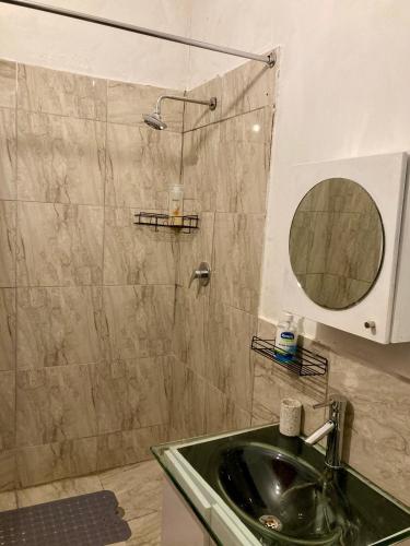 a bathroom with a sink and a shower with a mirror at Luxury Smart Studio - Sea and Mountain Views - Gordon's Bay in Gordonʼs Bay