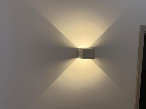eine Lampe an einer Wand mit einer weißen Wand in der Unterkunft Villa Cologne - Apartments & Monteursquartiere in Meckenheim bei Köln in Meckenheim