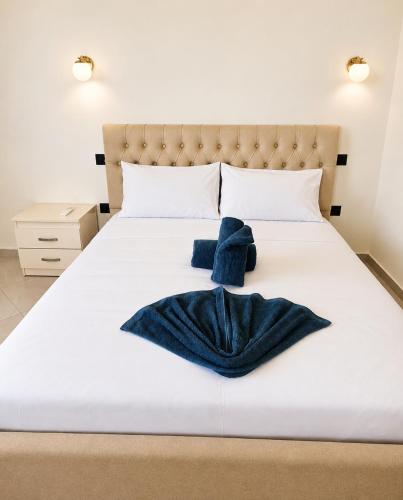 a white bed with a blue blanket on it at Rrapi Apartments in Tragjas