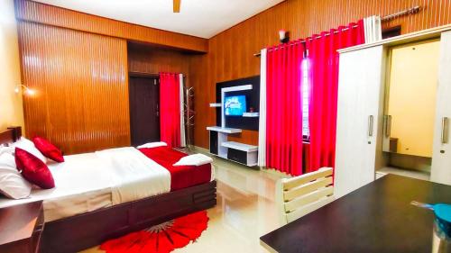 a bedroom with a bed with red curtains and a television at DevaDheyam Homestay in Munnar