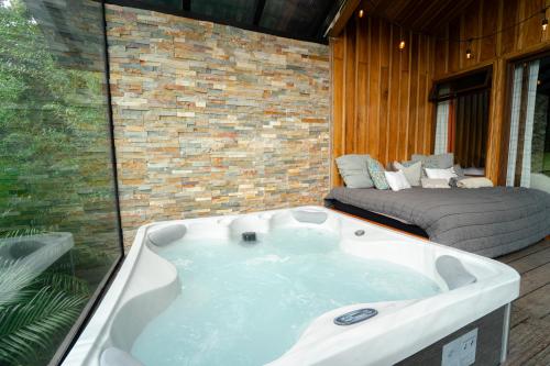 a bath tub in a room with a bed at Cabañas Hoja Verde in Monteverde Costa Rica