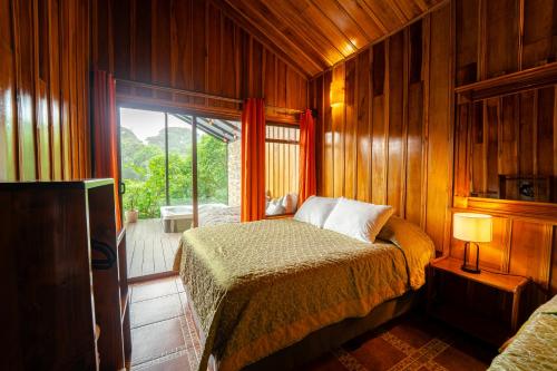 a bedroom with a bed and a sliding glass door at Cabañas Hoja Verde in Monteverde Costa Rica