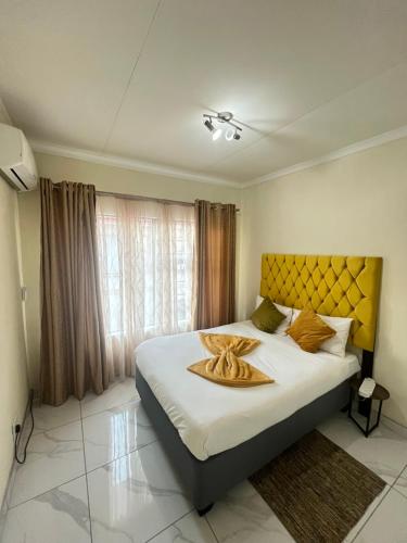 a bedroom with a large bed with a yellow headboard at Indumiso 80 in Newcastle