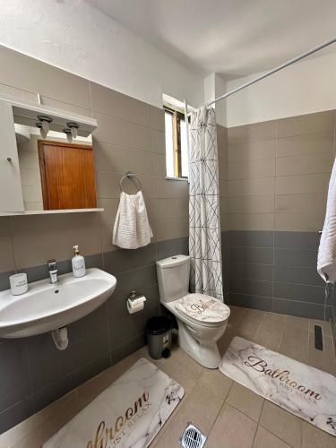 a bathroom with a sink and a toilet and towels at SDROSOS Apartment in Kos