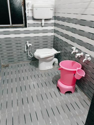 a bathroom with a toilet and a pink bucket at Radhe House in Dwarka