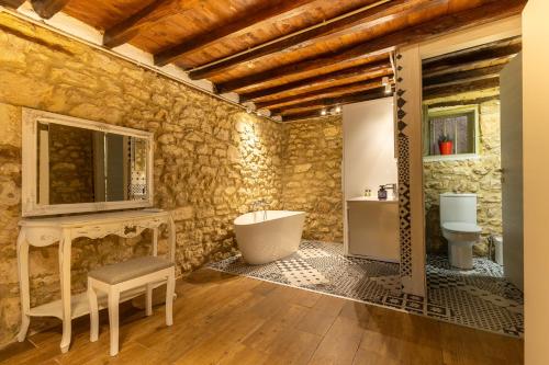 a stone walled bathroom with a tub and a sink at Stefanos House in Afitos