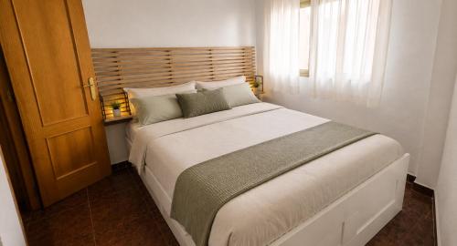 a bedroom with a large white bed and a window at Vistas al castillo in Cullera