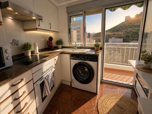 a kitchen with a washing machine and a window at Vistas al castillo in Cullera