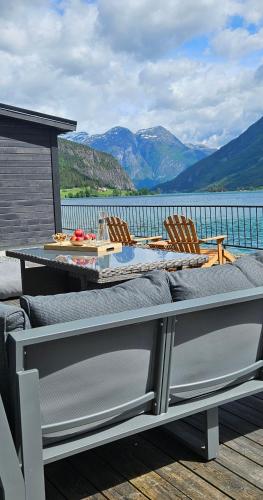 a table and chairs on a deck with a view of the water at Modern lakefront apt with view - EV plug in Stryn