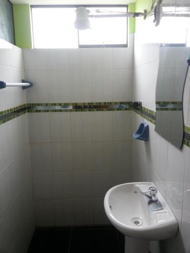Baño blanco con lavabo y espejo en Hostal Arcangel en Abancay