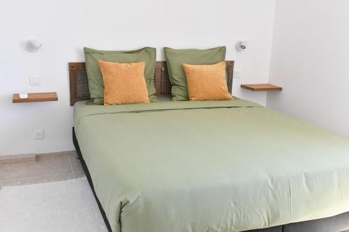 a large bed with green sheets and pillows at Résidence Gigaro plage in La Croix-Valmer