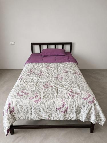 a bed with a purple and white comforter on it at Maréa - Casa en Lobitos in Lobitos