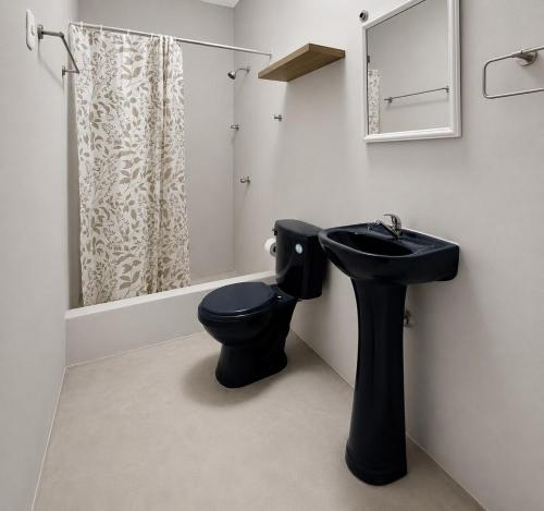 a bathroom with a black toilet and a sink at Maréa - Casa en Lobitos in Lobitos