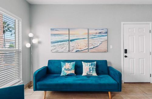 a blue couch in a living room with two paintings of the ocean at SPI Beach Condo - Just a block away to Paradise in South Padre Island