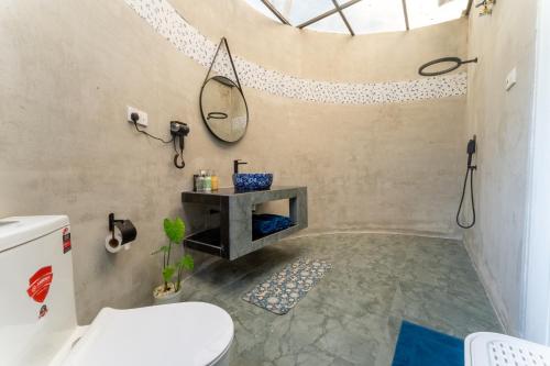 a bathroom with a toilet and a mirror on the wall at The black monkey villa - Private pool in Kosgoda