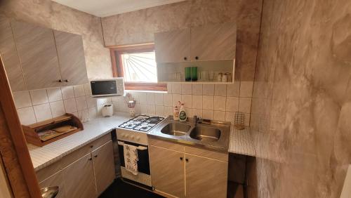 a small kitchen with a sink and a stove at Kicsi Rigó Vendégház in Bogács