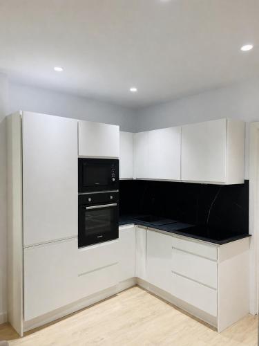 a kitchen with white cabinets and a black appliance at Palacios Centro - El Puerto in El Puerto de Santa María