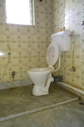 a bathroom with a white toilet in a room at Nalanda Tulip in Kolkata