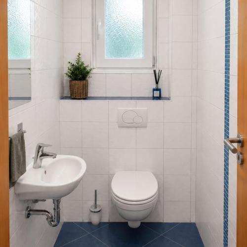 a white bathroom with a toilet and a sink at "schön-urlauben" in Gröbming
