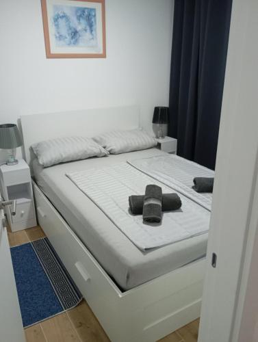 a white bed with two black towels on it at Apartment with pool in Veliko Gradište