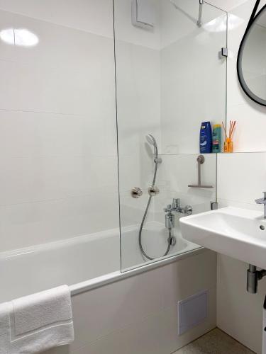 a white bathroom with a shower and a sink at Modra Sunny Apartment in Modra