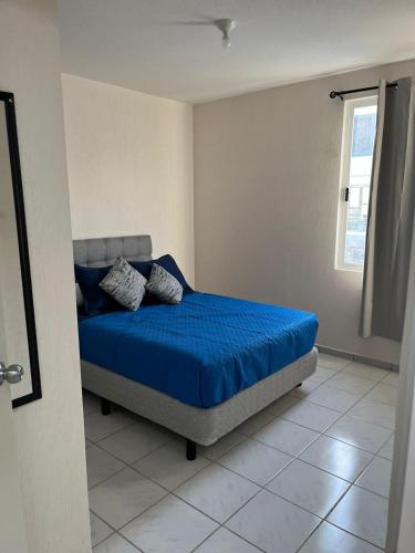 a bedroom with a bed with blue sheets and a window at Residencial Granate Xochitepec Morelos in Atlacholoaya