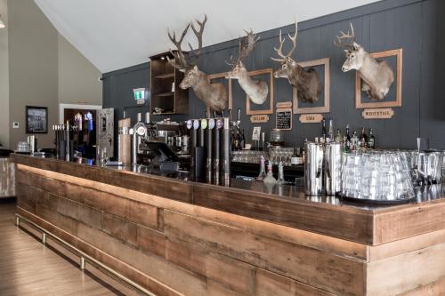 a bar with deer heads hanging on the wall at The Harvest Hotel in Cromwell