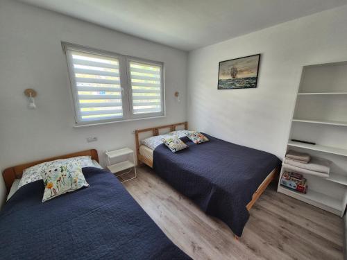 a bedroom with two beds and a window at Noclegi u Loni - Szary domek - noclegi w zacisznym centrum Pobierowa nad morzem z parkingiem in Pobierowo