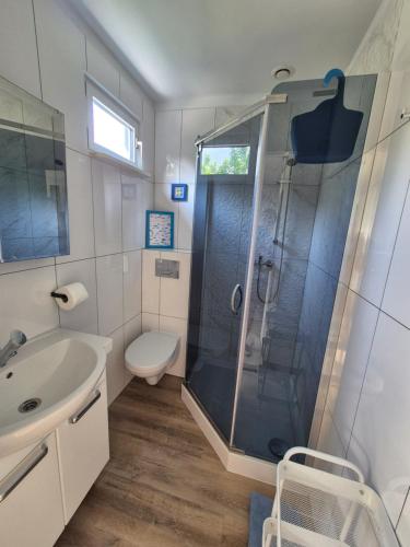 a bathroom with a shower and a toilet and a sink at Noclegi u Loni - Szary domek - noclegi w zacisznym centrum Pobierowa nad morzem z parkingiem in Pobierowo