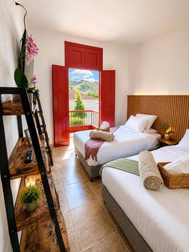 two beds in a room with a balcony at El Portón de Salento in Salento