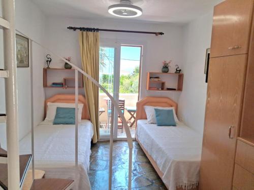 two beds in a room with a balcony at Villa Rena in Batsi