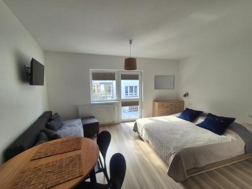 a bedroom with a bed and a couch and a table at Noclegi u Loni- pokoje studio w zacisznym centrum nad morzem z parkingiem in Pobierowo