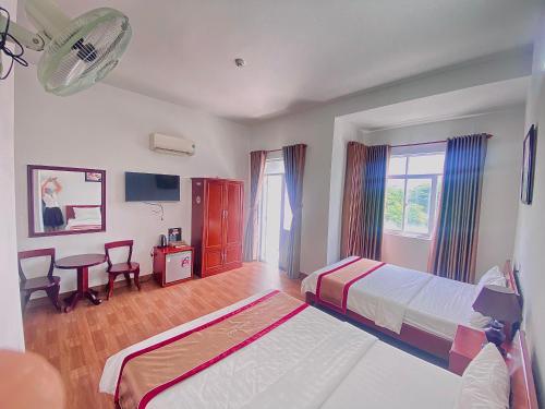 a bedroom with two beds and a desk and a table at Minh Thư Phú Mỹ Hotel in Phú Mỹ