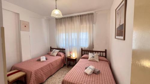 two beds in a small room with a window at Todimer Acera del Mar in Torrenueva