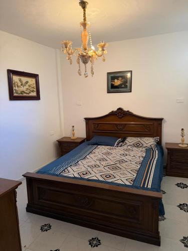 a bedroom with a bed and a chandelier at Radi in Menzel Jemil