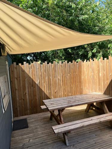 a wooden bench with a canopy on a wooden deck at Gite "home" - piscine in Juvigny-le-Tertre