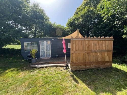 a tiny house with a wooden deck and a fence at Gite "home" - piscine in Juvigny-le-Tertre