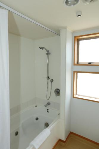 a white bathroom with a tub and a window at The Harvest Hotel in Cromwell