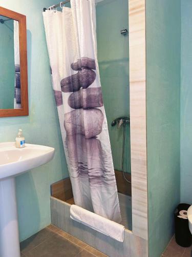 a bathroom with a shower curtain and a sink at Hotel Rocamar in Cala Figuera