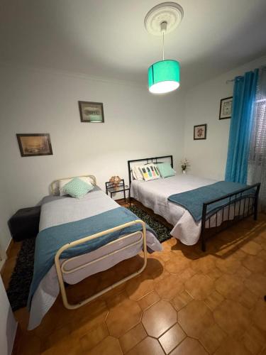 ein Schlafzimmer mit zwei Betten und grünem Licht in der Unterkunft House Calhambeque in Meimoa