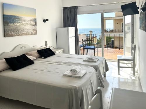 a bedroom with a large bed and a balcony at Hotel Rocamar in Cala Figuera