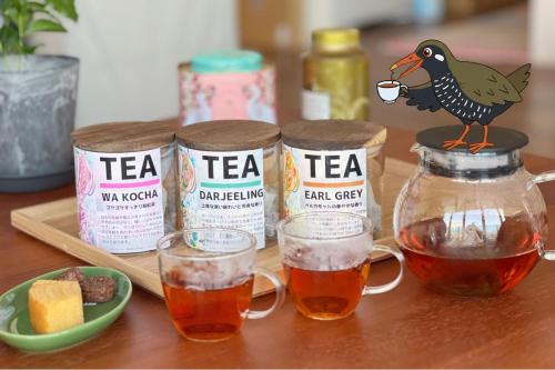 a table with two jars of tea and a bird drinking tea at OKINAWA BEACH HOUSE Golden Drop S in Yaka