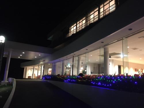 um edifício à noite com flores azuis e luzes em Amakusa Santacoming Hotel em Amakusa