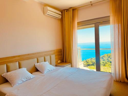 a bedroom with a bed and a large window at Skyline View Apt & Sea View Terrace in Budva
