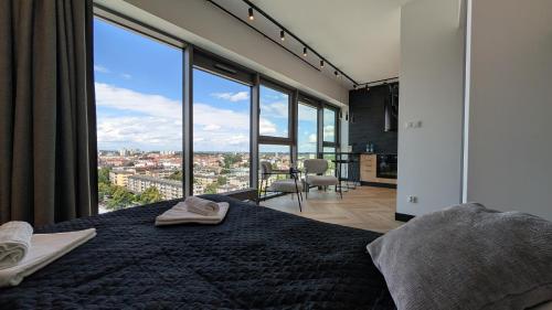 a bedroom with a bed with a large window at Apartament Loft Olszynki Park in Rzeszów