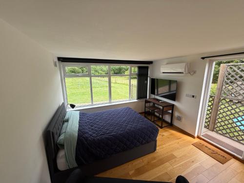 a bedroom with a bed and two large windows at Summerhouse in Honington
