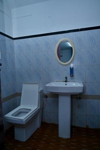 a bathroom with a sink and a toilet and a mirror at Sree Durga Veerabhoomi Resort in Kushālnagar