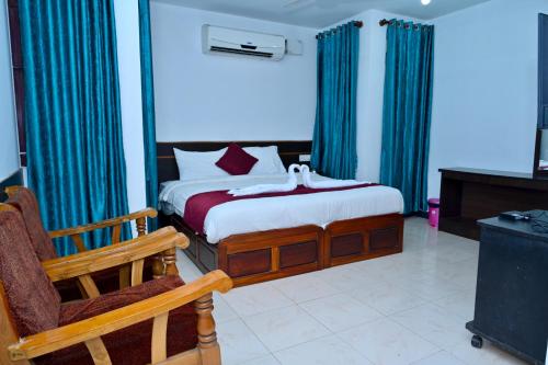 a bedroom with a bed with blue curtains and a chair at Sree Durga Veerabhoomi Resort in Kushālnagar