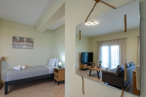a bedroom with a bed and a couch and a television at Anima Horizon - Terra apartment in Elaiófiton