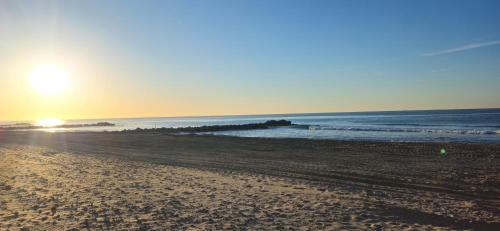 a beach with the sun rising over the ocean at Entre Ciel&Mer in Palavas-les-Flots